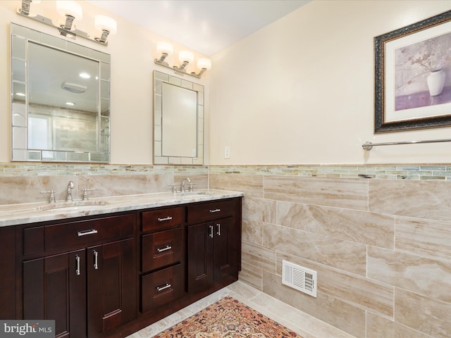 bathroom with tile walls, double vanity, wainscoting, and a shower