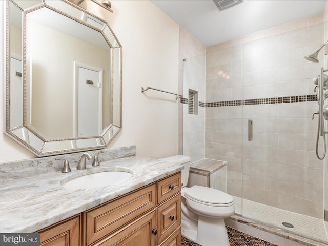 bathroom with a stall shower, toilet, vanity, and tile patterned floors