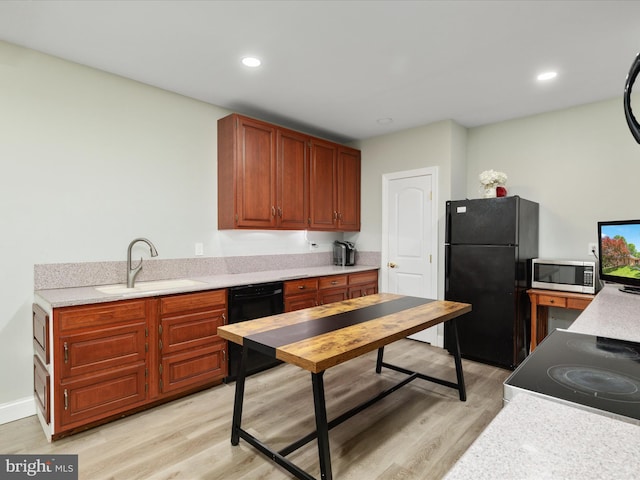 kitchen featuring a sink, black appliances, light wood-style floors, light countertops, and recessed lighting