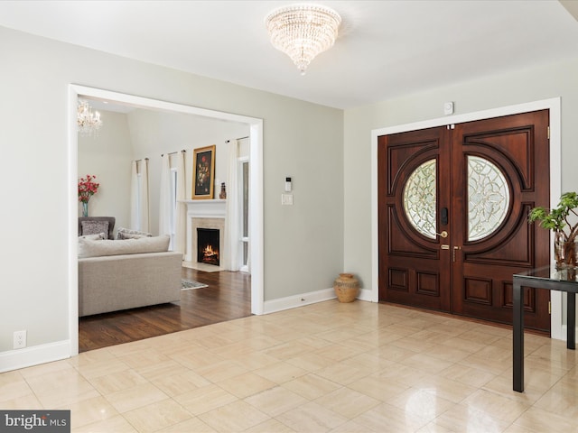 foyer entrance with a chandelier, french doors, and baseboards
