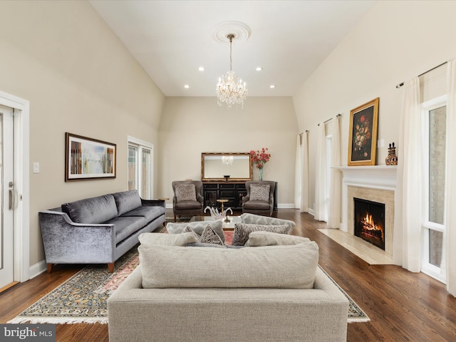 living area featuring a chandelier, a fireplace, recessed lighting, dark wood finished floors, and a high ceiling