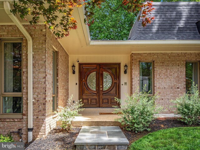 entrance to property with brick siding and a shingled roof