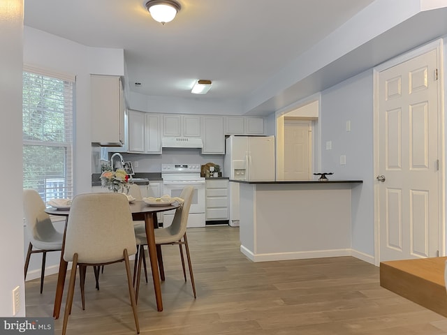 411 N Ln, Prince Frederick, MD 20678 - kitchen with white appliances, under cabinet range hood, a peninsula, dark countertops, and light wood finished floors