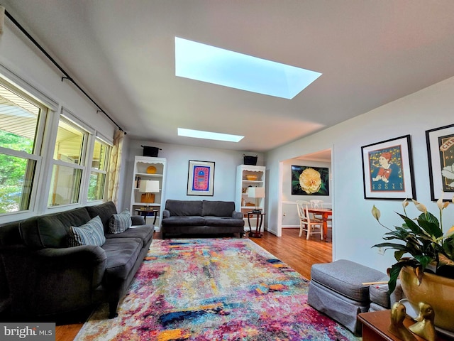 living area with a skylight and wood finished floors