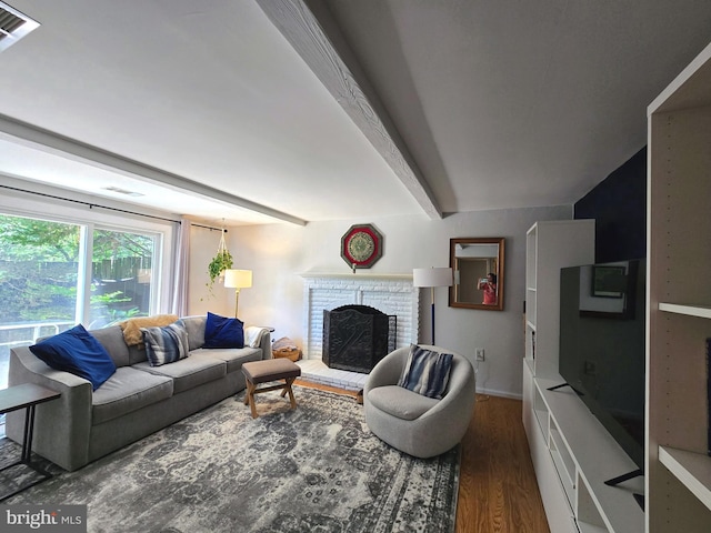 living room featuring beam ceiling, a brick fireplace, wood finished floors, and visible vents
