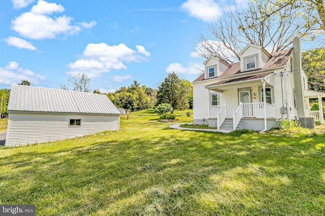 view of side of property featuring a yard, covered porch, a chimney, and central AC unit