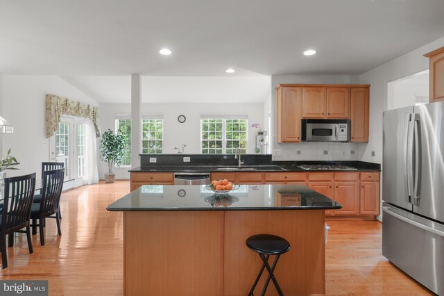 11404 Ramsburg Ct, North Potomac, MD 20878 - kitchen with appliances with stainless steel finishes, light wood finished floors, a kitchen bar, a kitchen island, and a sink