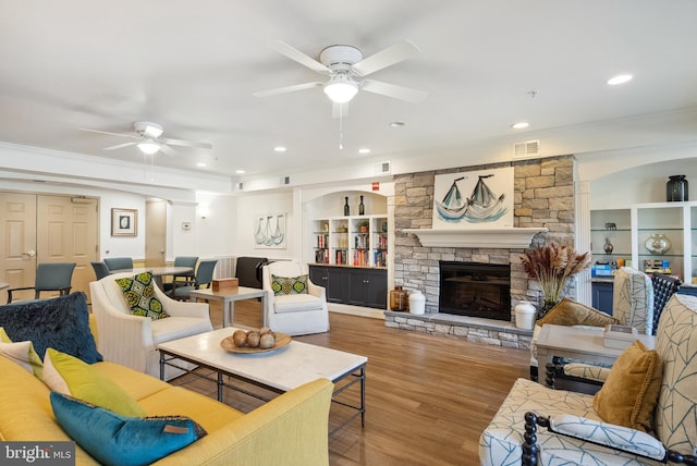 living room with crown molding, ceiling fan, wood finished floors, and visible vents