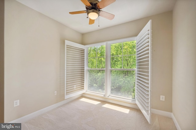 carpeted empty room with baseboards and a ceiling fan