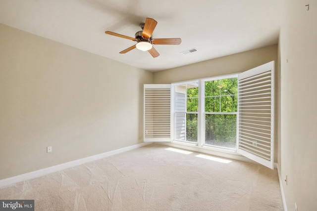 carpeted spare room with ceiling fan, visible vents, and baseboards
