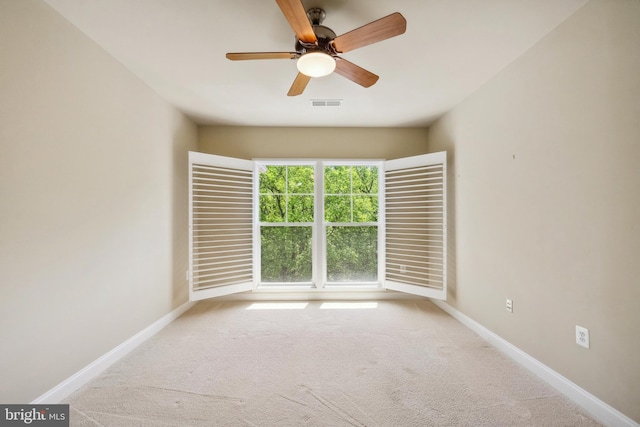 carpeted spare room featuring a ceiling fan, baseboards, and visible vents
