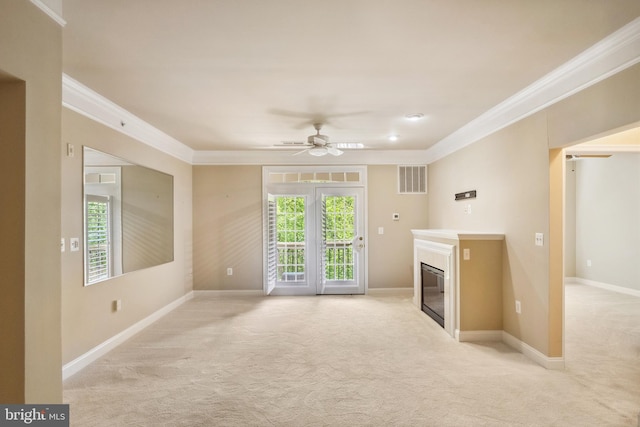 unfurnished living room with a glass covered fireplace, ornamental molding, visible vents, and light colored carpet