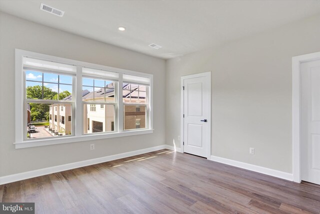 unfurnished room featuring healthy amount of natural light, wood finished floors, baseboards, and recessed lighting