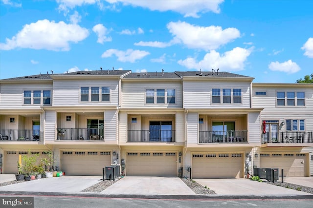 view of property featuring an attached garage, central AC, and driveway