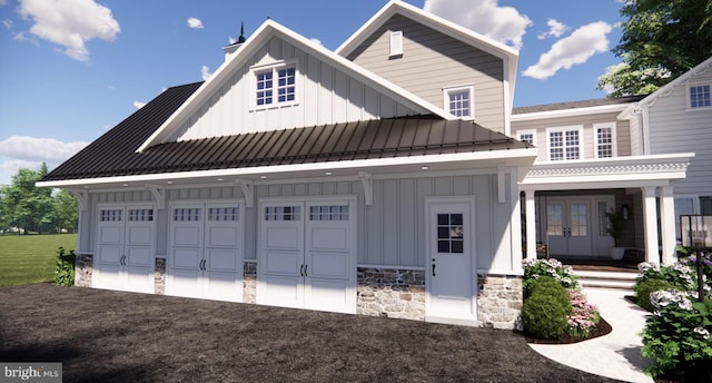 view of front of home featuring a garage, stone siding, french doors, a standing seam roof, and board and batten siding