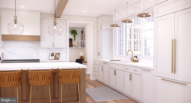 kitchen featuring a sink, tasteful backsplash, white cabinetry, and decorative light fixtures