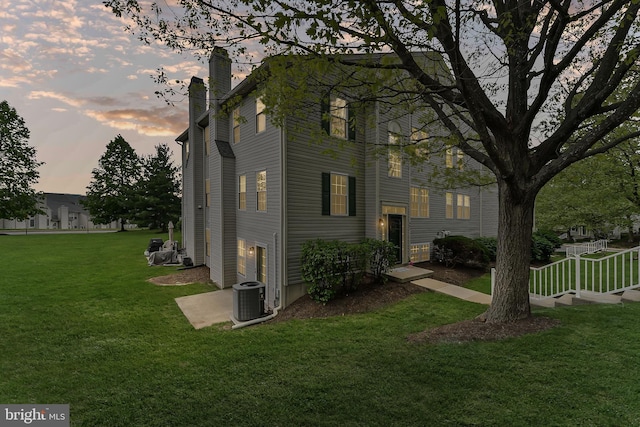 493 Stoneglen St, Collegeville, PA 19426 - property exterior at dusk with a lawn, central AC, and a chimney