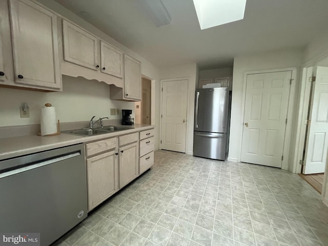kitchen with light countertops, a skylight, appliances with stainless steel finishes, and a sink