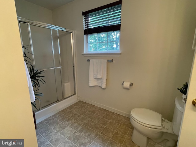 full bathroom featuring toilet, a shower with door, baseboards, and tile patterned flooring