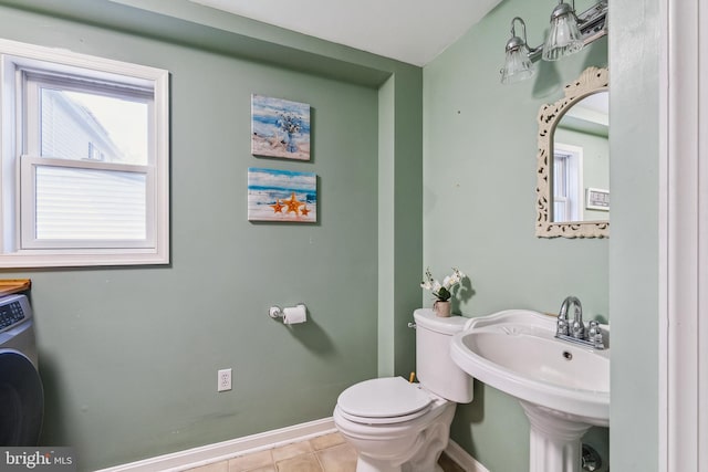 half bath featuring washer / clothes dryer, tile patterned flooring, a sink, baseboards, and toilet