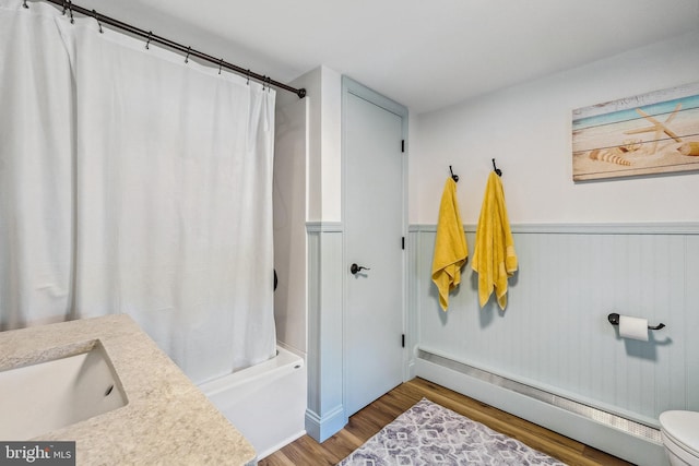 full bath with wood finished floors, a sink, a baseboard radiator, toilet, and shower / bath combo with shower curtain