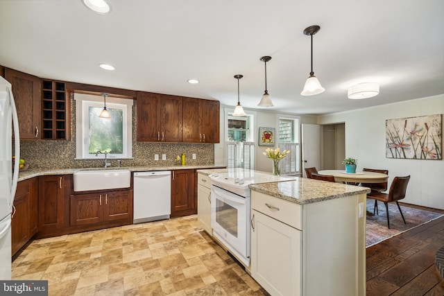kitchen with light stone countertops, a sink, white appliances, decorative light fixtures, and decorative backsplash