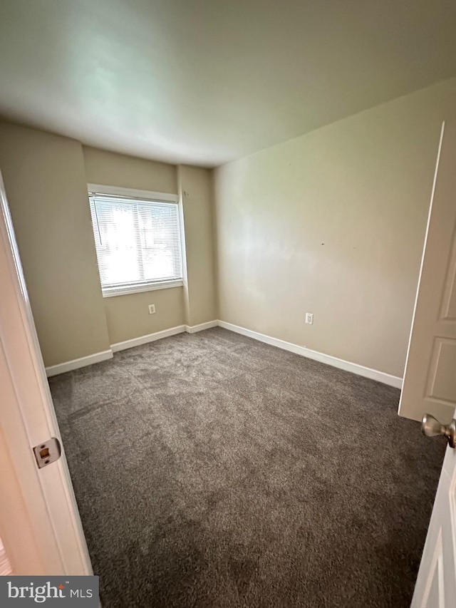 unfurnished bedroom with baseboards and dark colored carpet