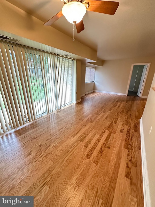 unfurnished living room with baseboards, a ceiling fan, wood finished floors, and visible vents