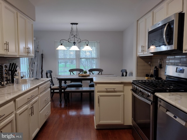 kitchen featuring appliances with stainless steel finishes, decorative backsplash, dark wood finished floors, and light stone counters