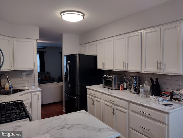 kitchen featuring a sink, freestanding refrigerator, white cabinetry, a toaster, and backsplash