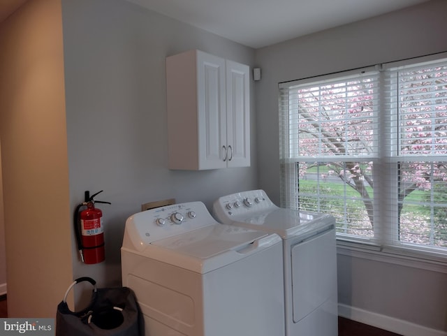 clothes washing area with cabinet space, washing machine and dryer, and a healthy amount of sunlight