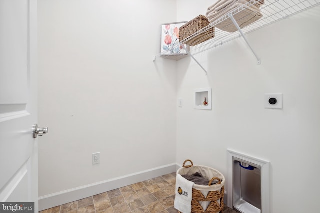 laundry area featuring washer hookup, stone finish floor, laundry area, electric dryer hookup, and baseboards