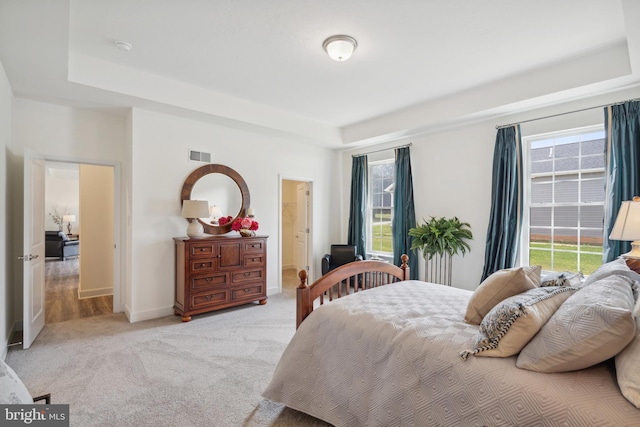 bedroom with visible vents, a raised ceiling, baseboards, and light carpet
