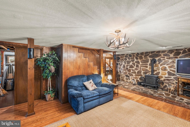 111 Heron Ln, Augusta, WV 26704 - living area featuring wood finished floors, a wood stove, stairway, a chandelier, and a textured ceiling