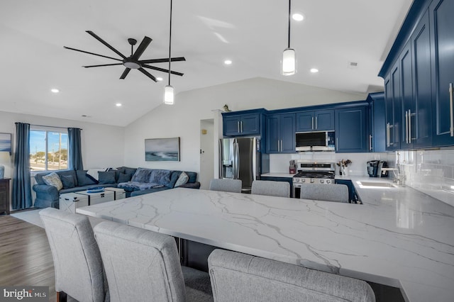 kitchen featuring a peninsula, appliances with stainless steel finishes, blue cabinetry, and lofted ceiling