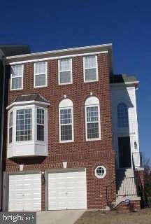 multi unit property featuring brick siding, driveway, and a garage
