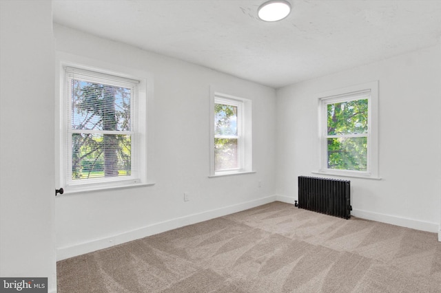 carpeted spare room with baseboards and radiator heating unit