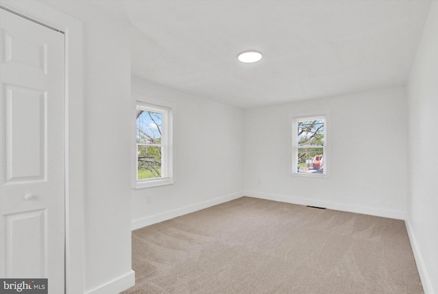 carpeted empty room featuring baseboards, a healthy amount of sunlight, and visible vents