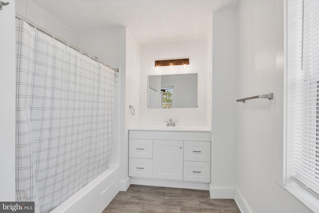 bathroom with baseboards, shower / bath combo, and vanity