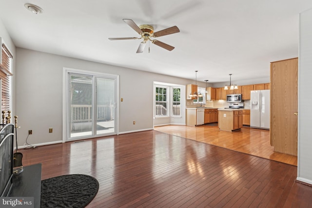 living room featuring a chandelier, ceiling fan, light wood-style floors, and baseboards
