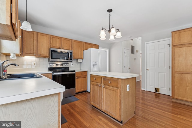 kitchen with stainless steel appliances, a sink, wood finished floors, and tasteful backsplash