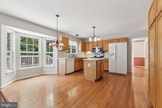 kitchen featuring stainless steel appliances, a chandelier, a sink, light countertops, and light wood-type flooring