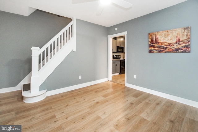 interior space with baseboards, ceiling fan, light wood-style flooring, and stairway