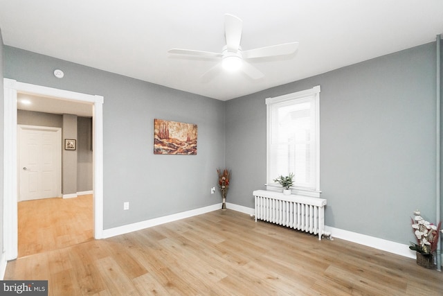 empty room featuring light wood-type flooring, radiator, and baseboards