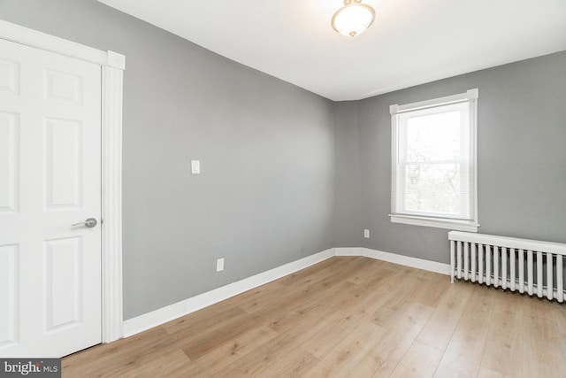 spare room with light wood-style floors, radiator, and baseboards