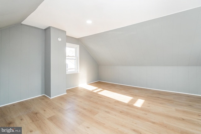 bonus room featuring light wood-style floors, baseboards, and vaulted ceiling
