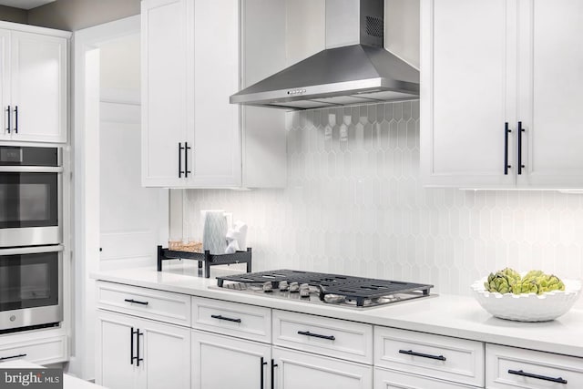 2682 Broadhorn Dr, Odenton, MD 21113 - kitchen with tasteful backsplash, white cabinetry, light countertops, stainless steel appliances, and wall chimney exhaust hood
