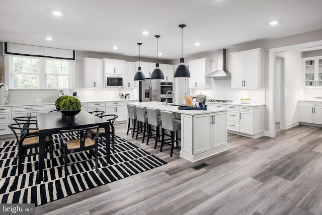 2682 Broadhorn Dr, Odenton, MD 21113 - kitchen with light wood-style floors, decorative backsplash, wall chimney exhaust hood, and stainless steel appliances