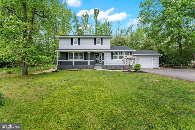 traditional-style home featuring covered porch, a front yard, a garage, fence, and aphalt driveway