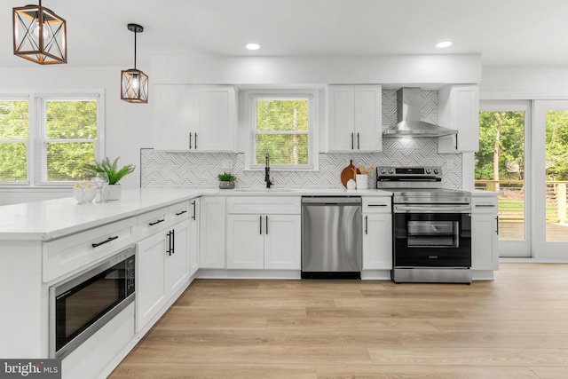 kitchen with a sink, wall chimney exhaust hood, backsplash, and stainless steel appliances